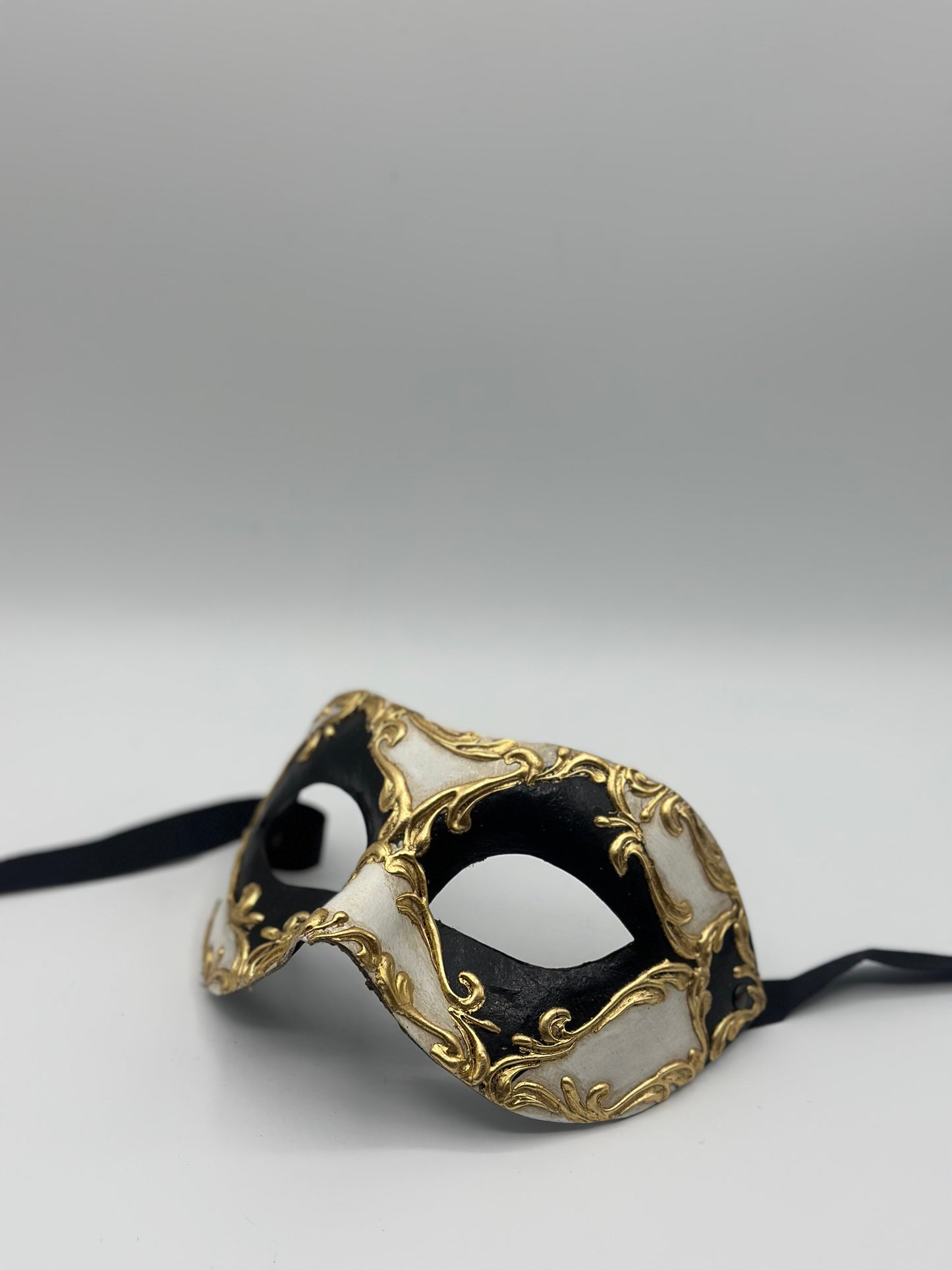 Schwarz-weiße venezianische Maske mit goldenen Barockdetails