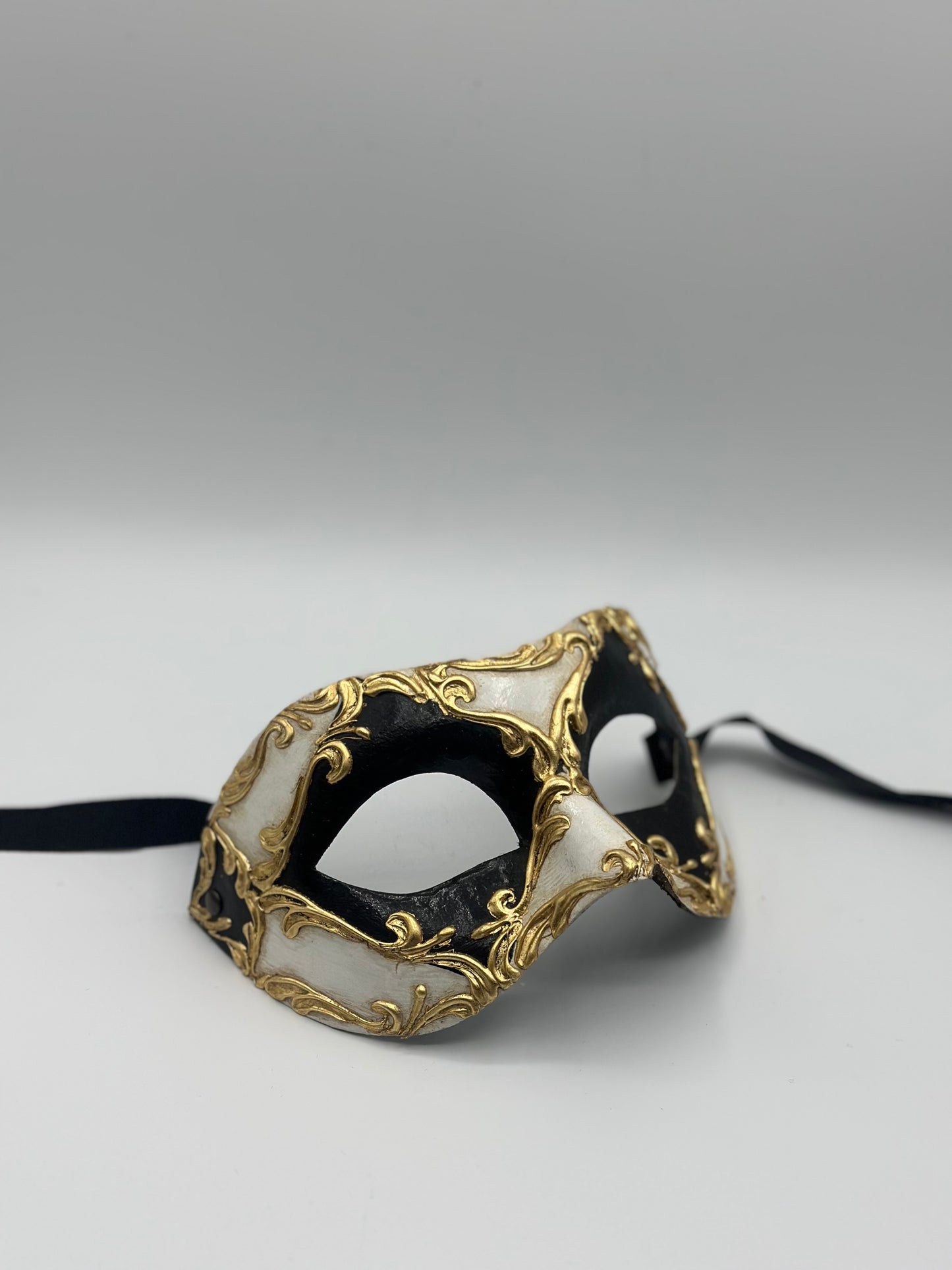 Schwarz-weiße venezianische Maske mit goldenen Barockdetails